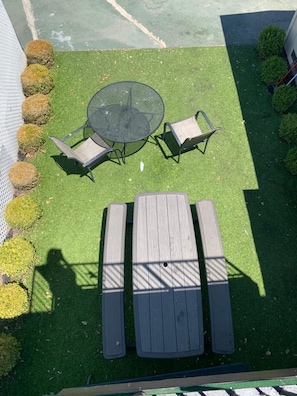 Área externa com mesa redonda e duas cadeiras, cercada por um banco de madeira.