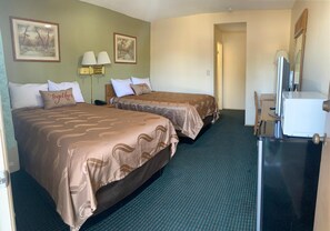A hotel room with two beds, a desk with a computer, and a mirror.