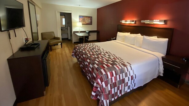 A hotel room with a large bed, a desk, a TV, and a small kitchenette. - California Inn & Suites Rancho Cordova - Sacramento (Rancho Cordova)