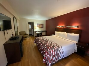 A hotel room with a large bed, a desk, a TV, and a small kitchenette. - California Inn & Suites Rancho Cordova - Sacramento (Rancho Cordova)