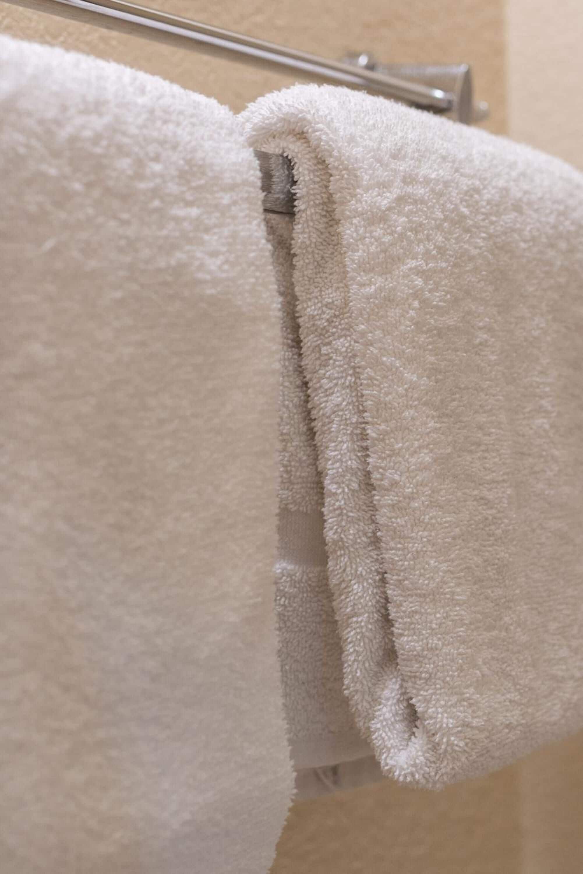 A folded white towel on a metal towel rack.