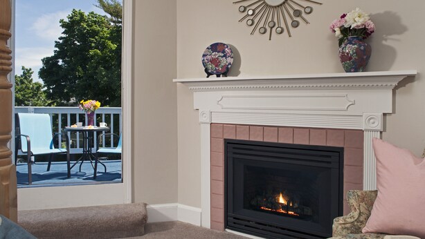 A living room with a fireplace, a dining table with chairs, and a view of the outdoors. - Beech Tree Inn & Cottage (Newport)