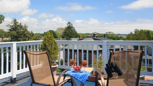 A balcony with a table, two chairs, a potted plant, and binoculars. - Beech Tree Inn & Cottage (Newport)