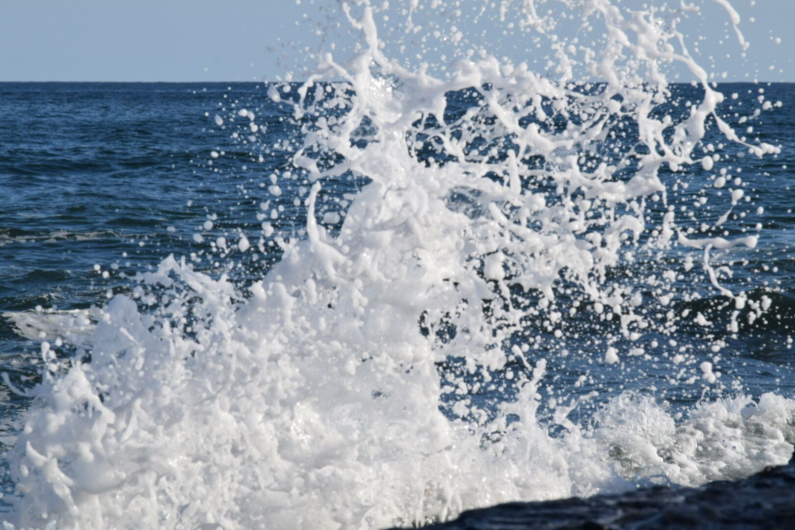 A close-up of a wave crashing against a rocky shore.