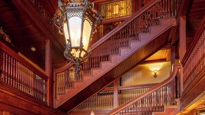 A grand staircase with ornate railings and a chandelier, leading to a second floor. - Ivy Lodge Bed & Breakfast (Newport)