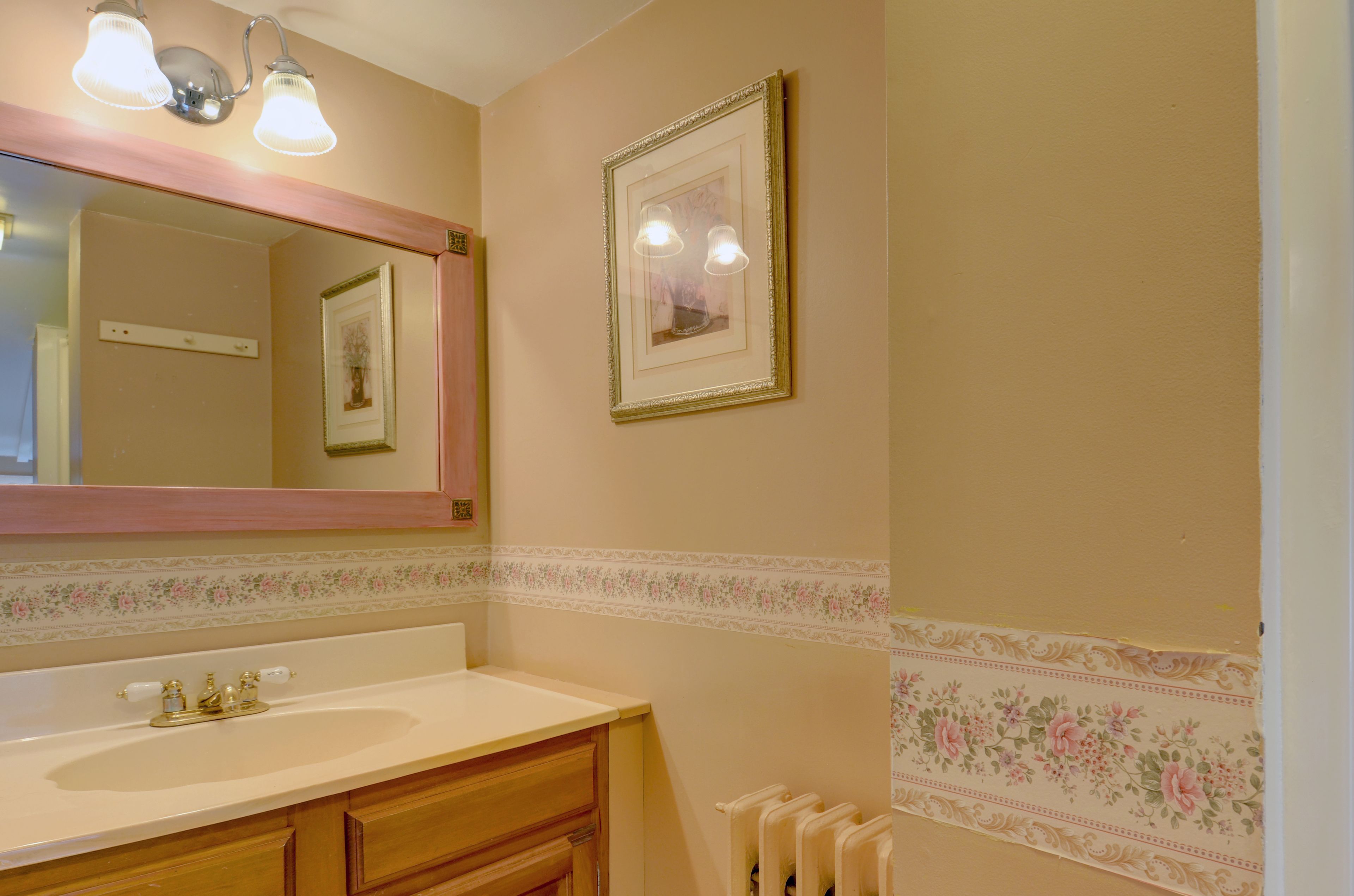 Une salle de bain avec un lavabo, un miroir et un tableau encadré au mur.