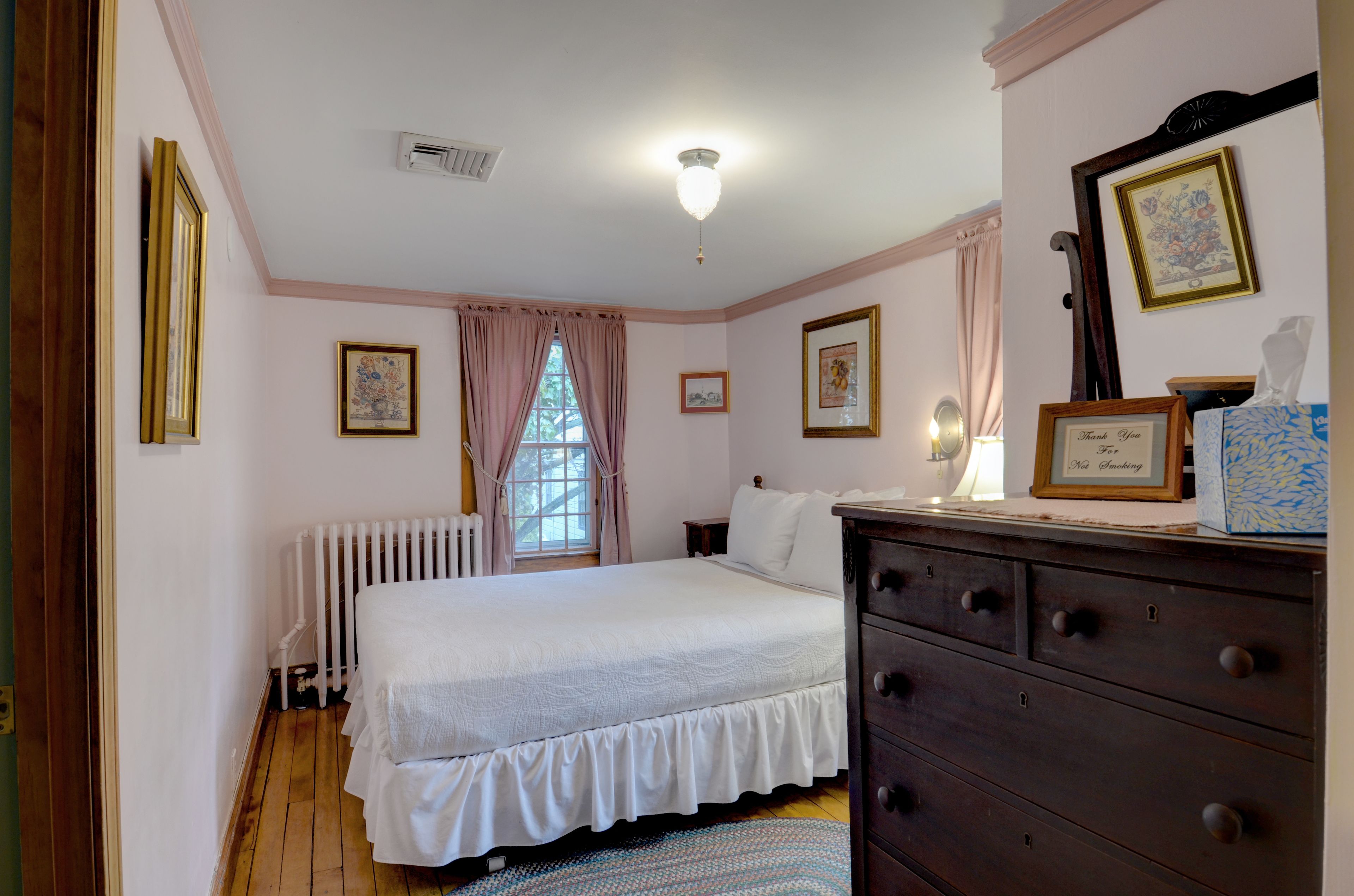 A bedroom with a bed, dresser, and framed pictures on the wall.