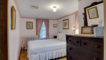 A bedroom with a bed, dresser, and framed pictures on the wall.