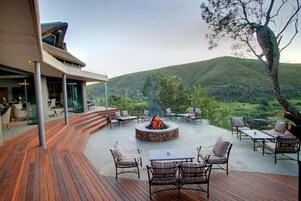 Terraza exterior con una chimenea, asientos y vistas del paisaje circundante.