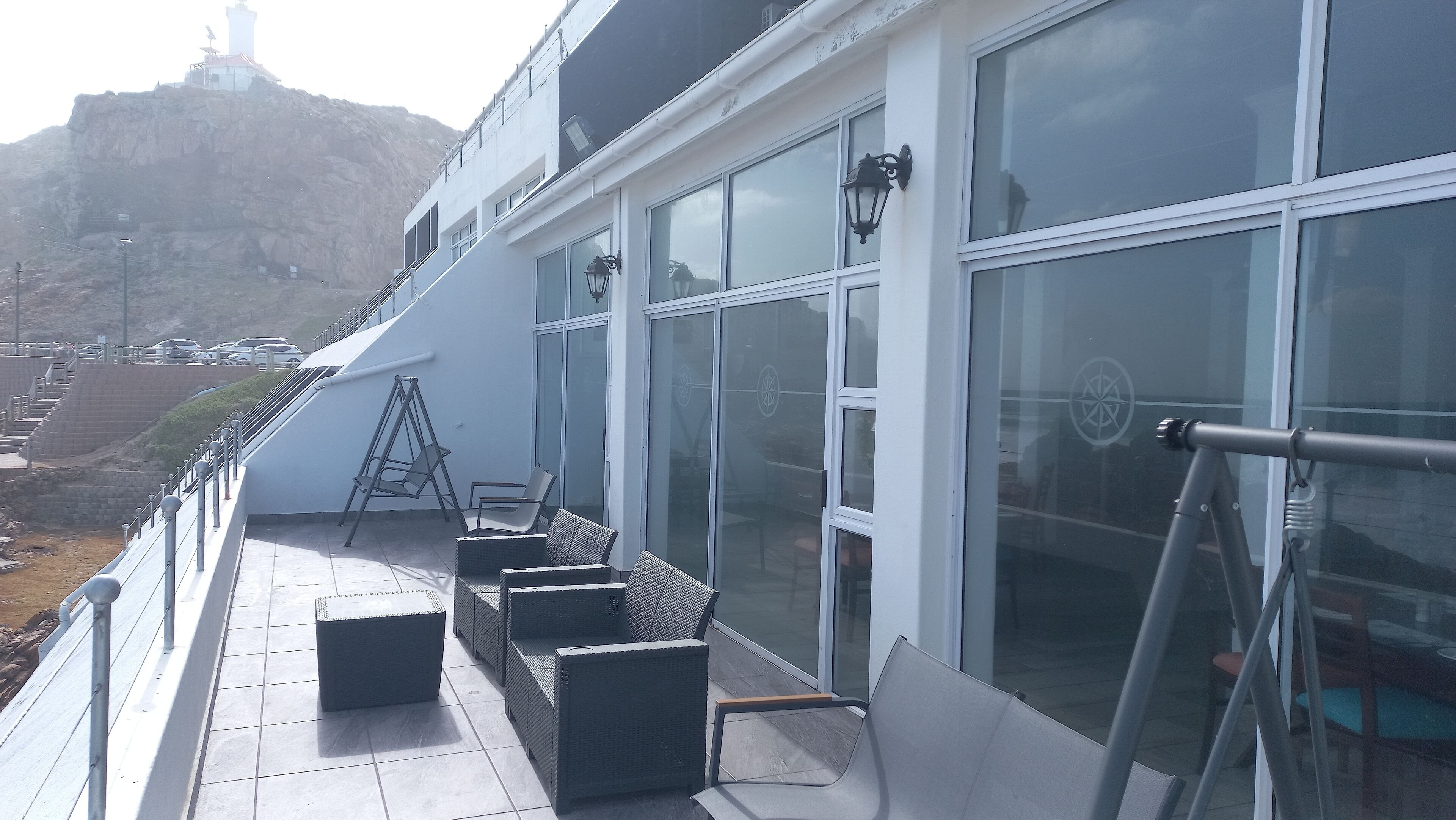 A balcony with outdoor seating, a ladder, and a view of a mountain.
