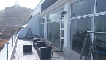 A balcony with outdoor seating, a ladder, and a view of a mountain.