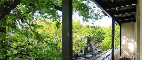 Un balcón techado con vistas a una calle arbolada.