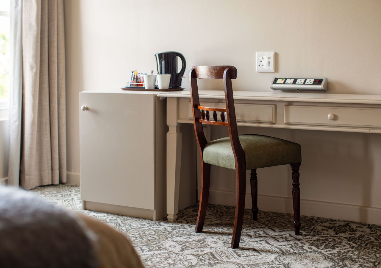 A compact kitchenette with a refrigerator, a coffee maker, and a power strip on the wall.