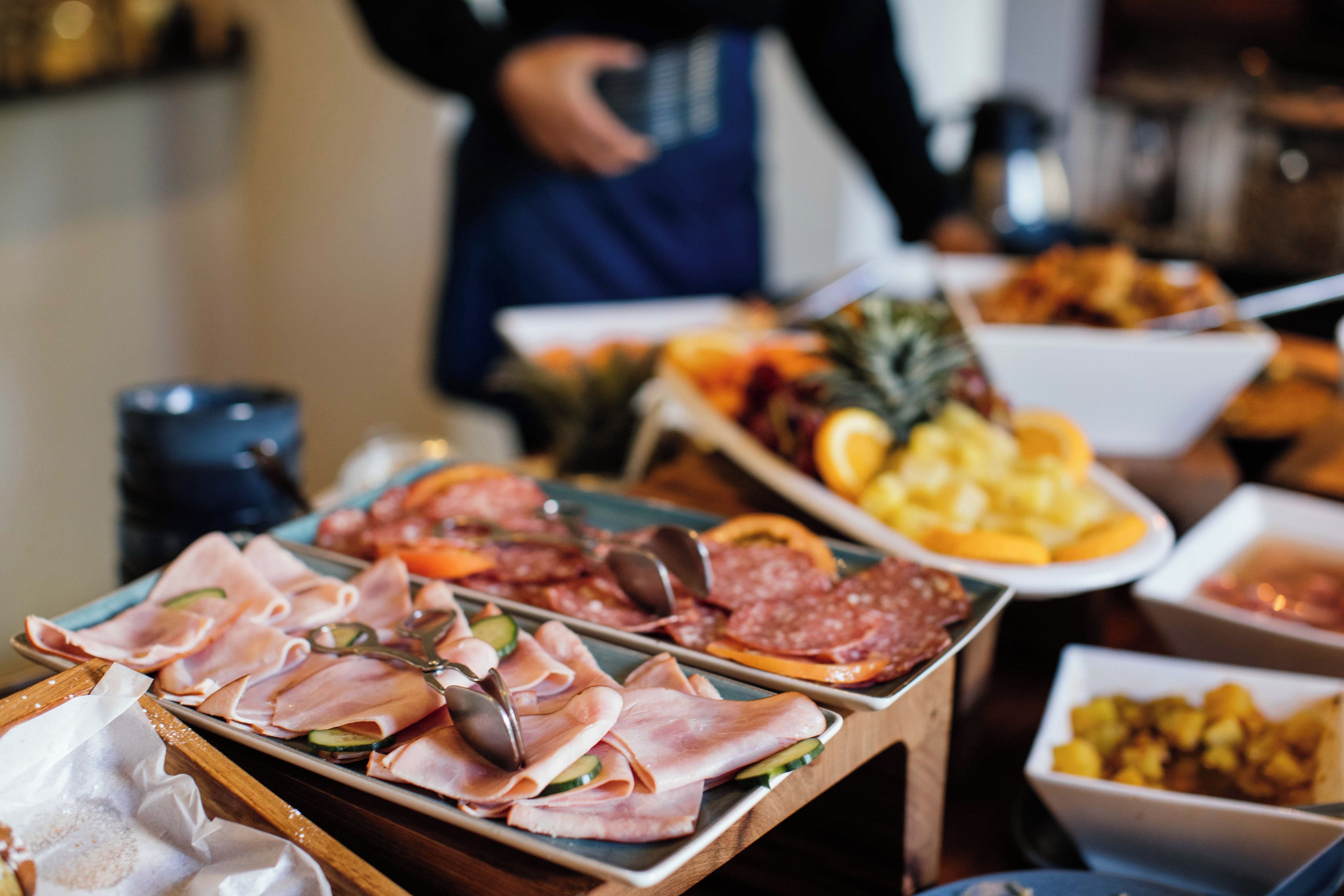 Una mesa de buffet con diversos alimentos, como carnes, frutas y verduras.