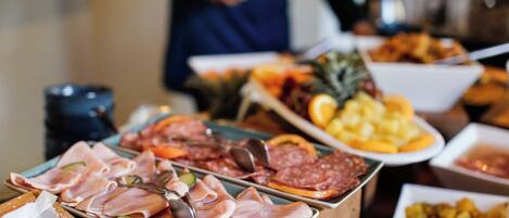 Una mesa de buffet con diversos alimentos, como carnes, frutas y verduras.