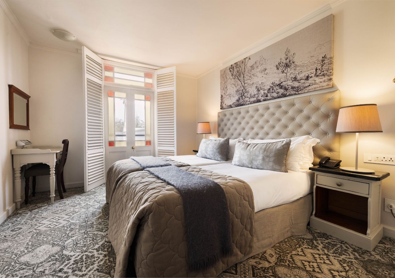 A bedroom with a bed, bedside tables, a desk, and a chair.