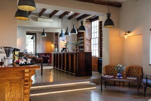A spacious kitchen with a central island, pendant lighting, and a view of the dining area. - The Stellenbosch Hotel (Stellenbosch)
