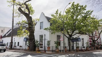 A white building with a black roof, a pedestrian crossing sign, and a street lamp.