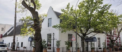 A white building with a black roof, a pedestrian crossing sign, and a street lamp.