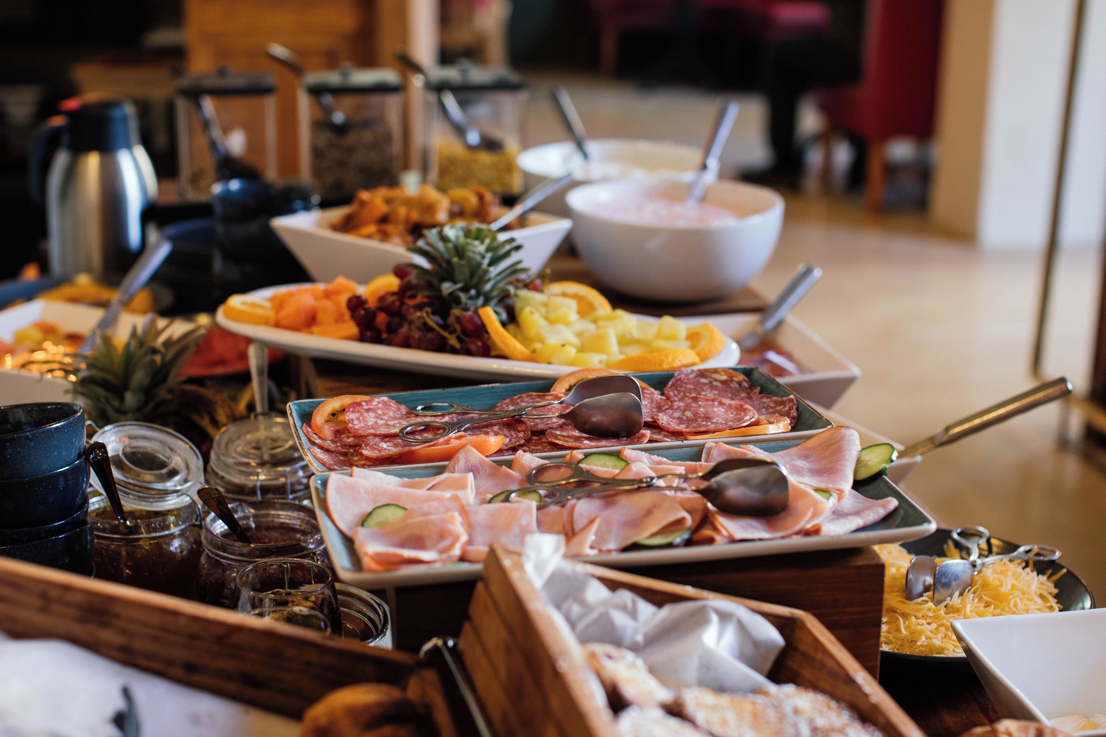 A buffet table with various food items including fruits, meats, and cheeses.