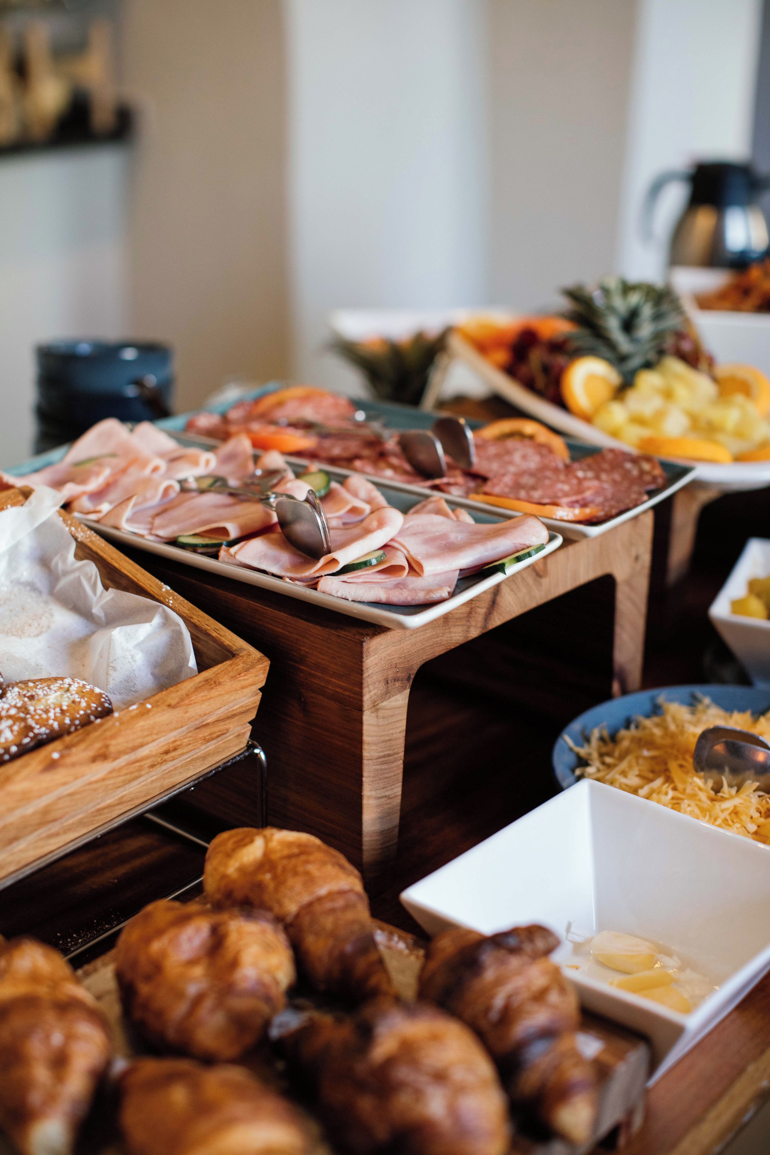 A buffet table with various food items including meats, cheeses, and pastries.