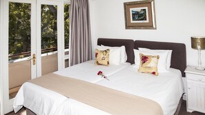 Una habitación de hotel con una cama grande, dos almohadas, una mesita de noche con una lámpara y un cuadro enmarcado en la pared.