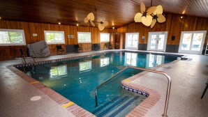 Una piscina interior con agua cristalina, paredes de madera y ventiladores de techo.