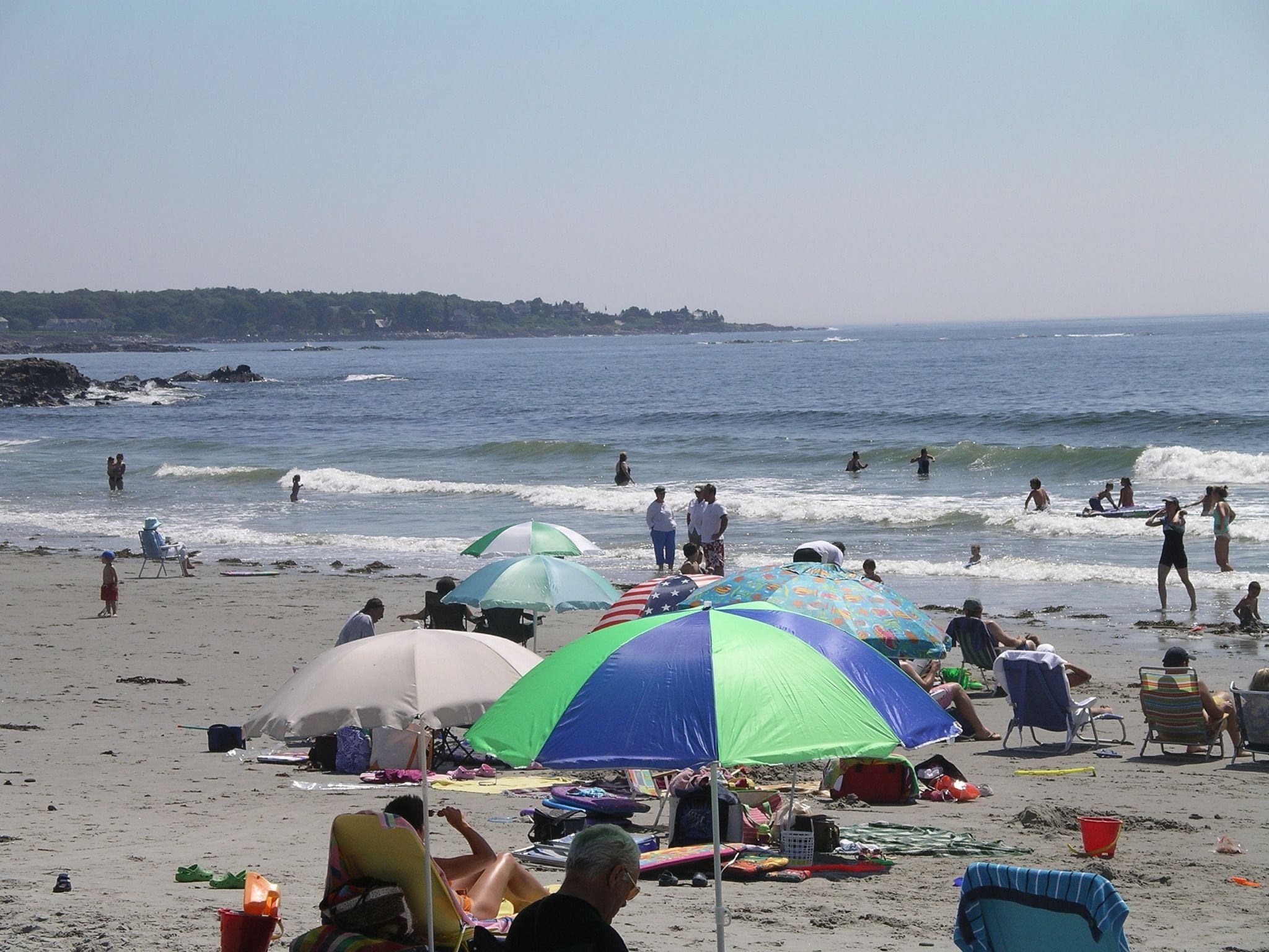 A beach with umbrellas, people, and the ocean.