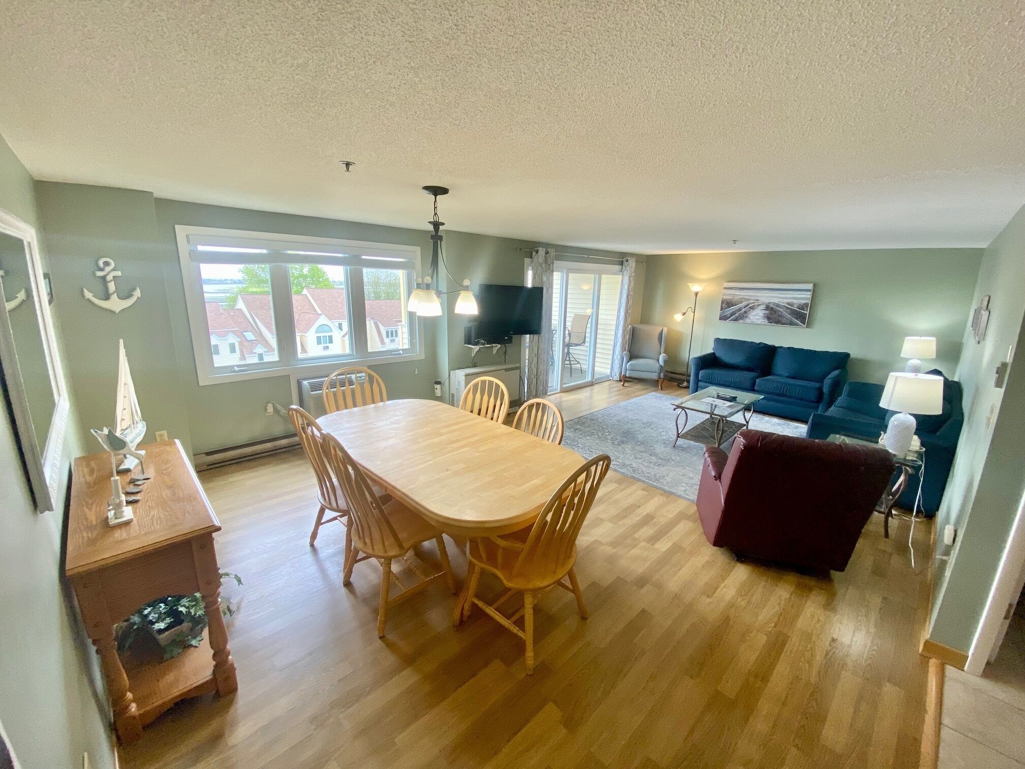 A spacious living area with a wooden dining table, a blue sofa, and a red armchair.