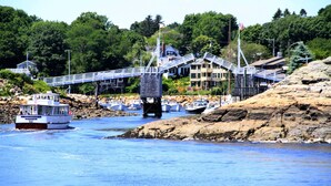 A coastal town with a bridge connecting two areas, boats docked near the shore, and buildings with visible architecture. - Village by the Sea (Wells)
