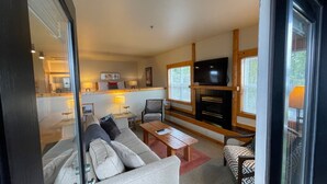 Ein modernes Wohnzimmer mit Sofa, Sesseln, Couchtisch, Kamin und Fernseher.