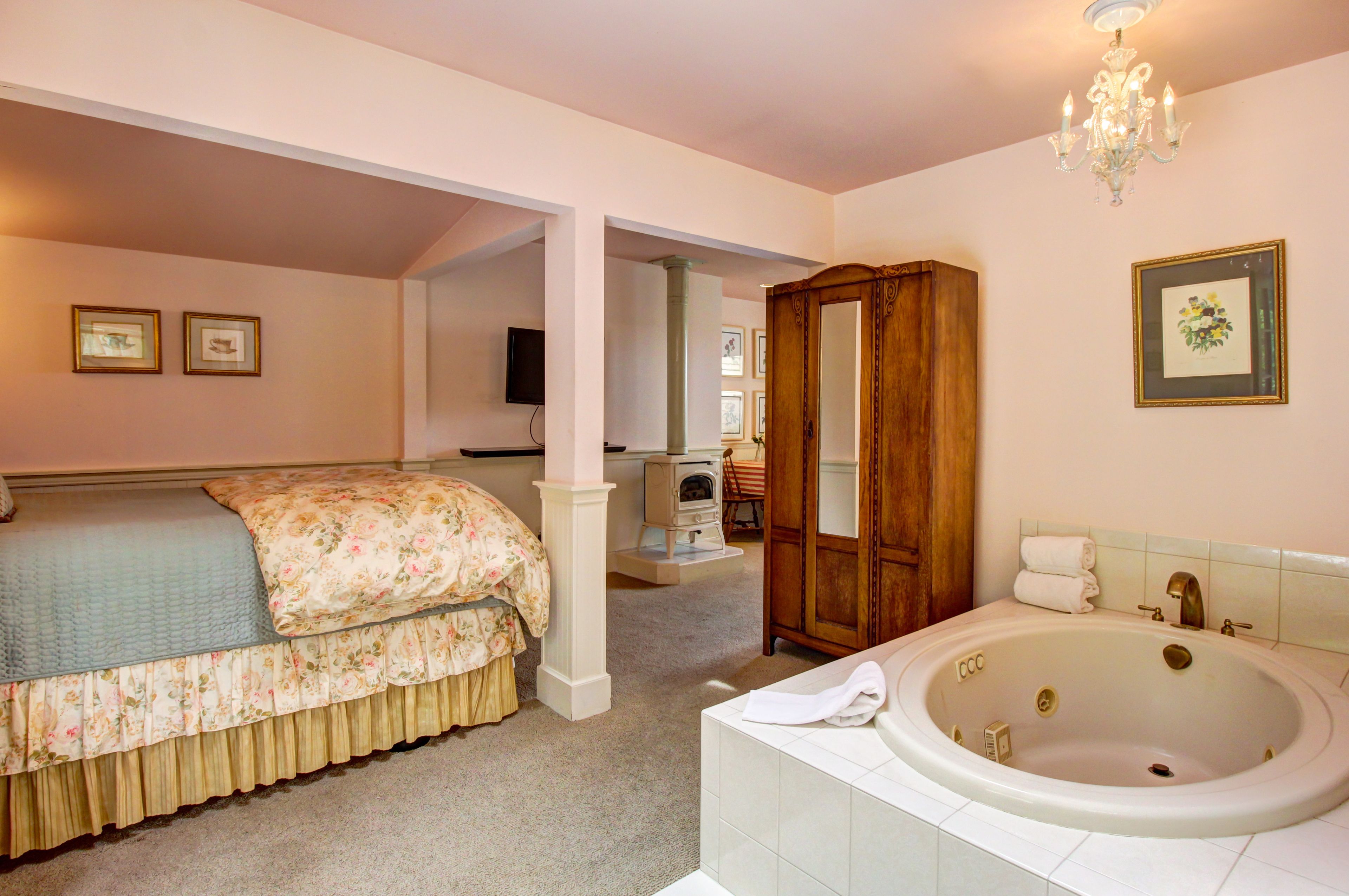 Une chambre à coucher avec un lit, une armoire en bois et une salle de bain avec une baignoire.