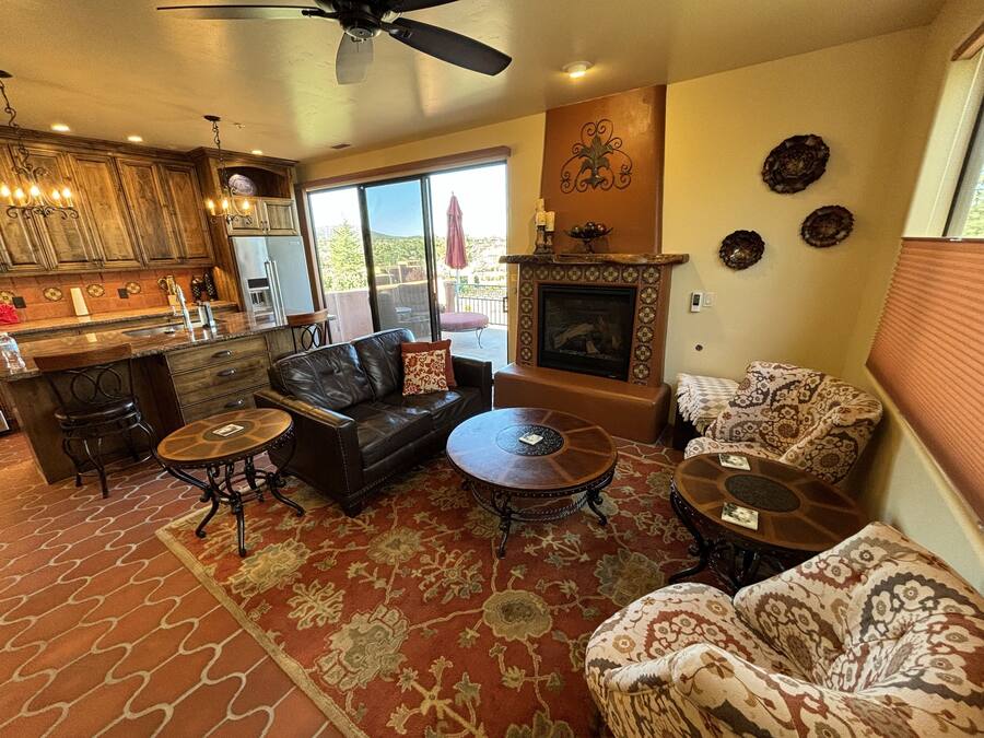 A spacious living room with a fireplace, leather sofa, and a dining area with a bar.