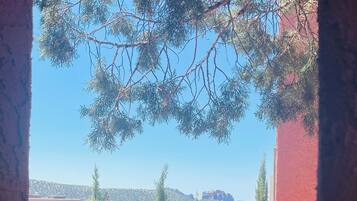A view through a window with a view of a red building, trees, and a clear blue sky.
