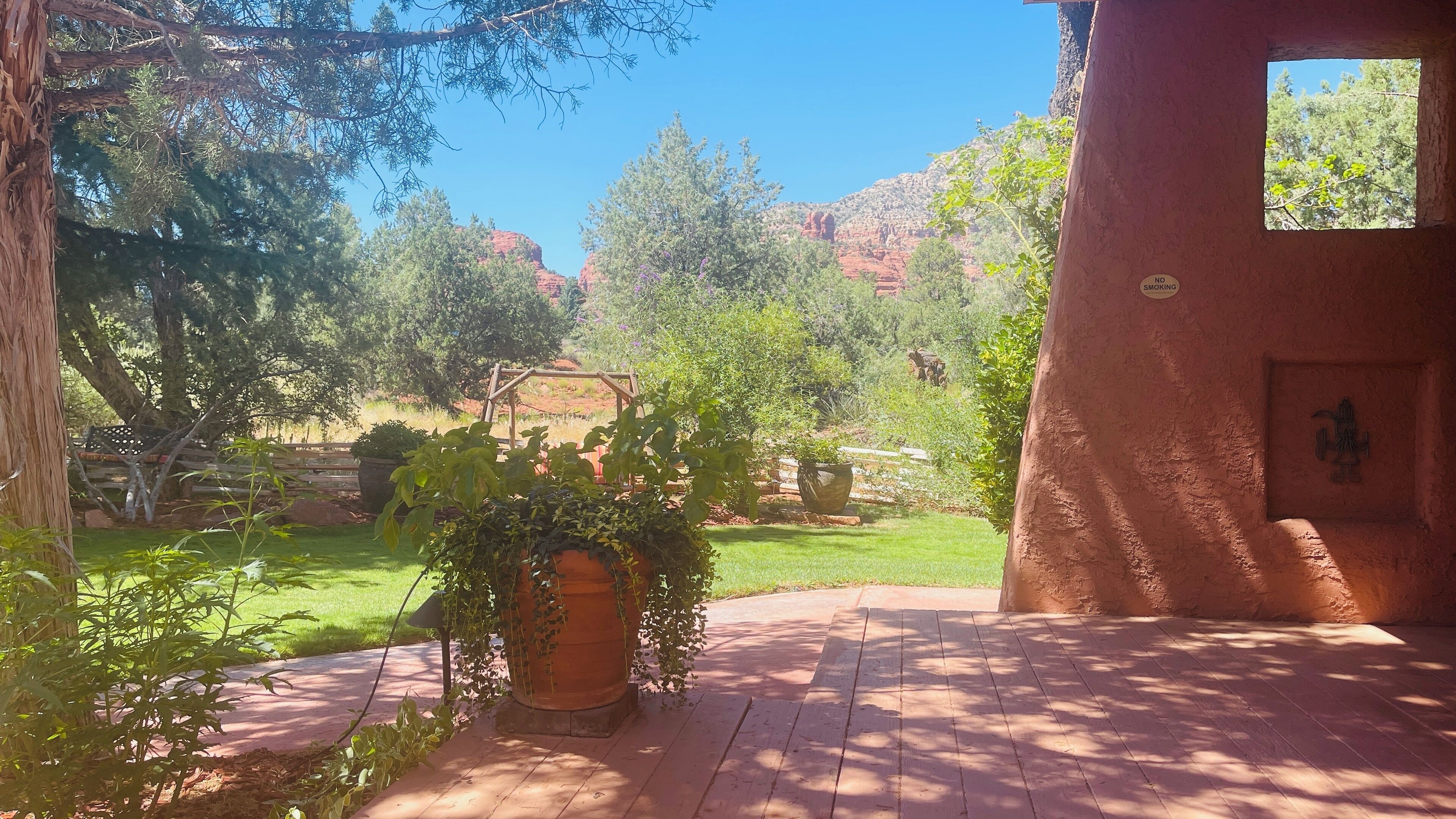 A patio area with a view of a landscaped garden and distant red rock formations.