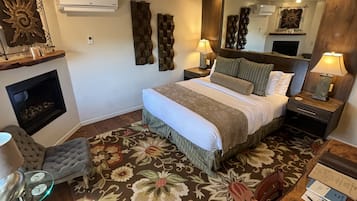 A hotel room with a large bed, two bedside tables, a chair, a small table, and a mirror.
