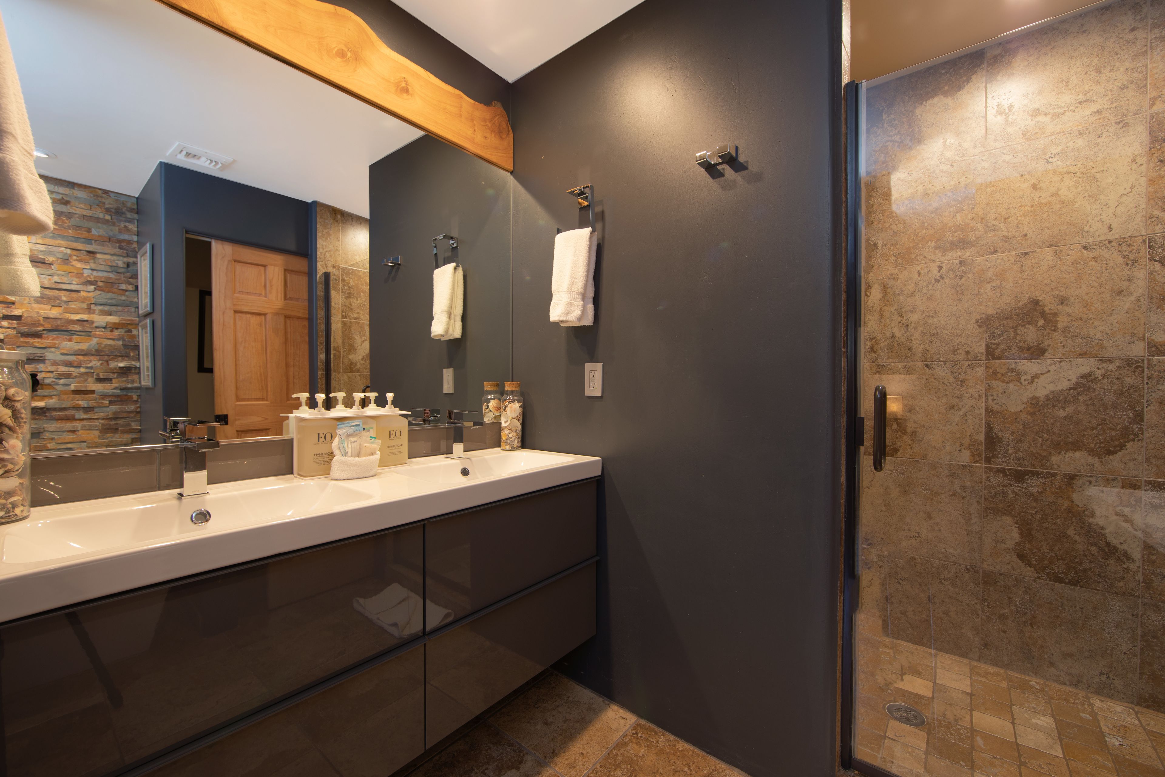 Un baño moderno con lavamanos doble, un espejo grande y zona de ducha.