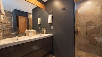 Un baño moderno con lavamanos doble, un espejo grande y zona de ducha.