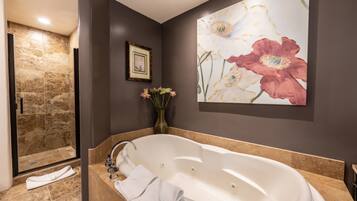 Une salle de bain avec une grande baignoire, un espace douche et un tableau encadré au mur.