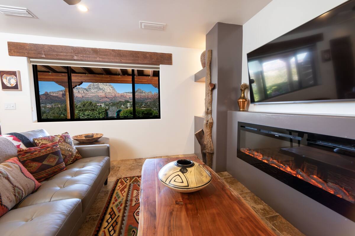 A modern living room with a sofa, a wooden coffee table, a flat-screen TV, and a fireplace.