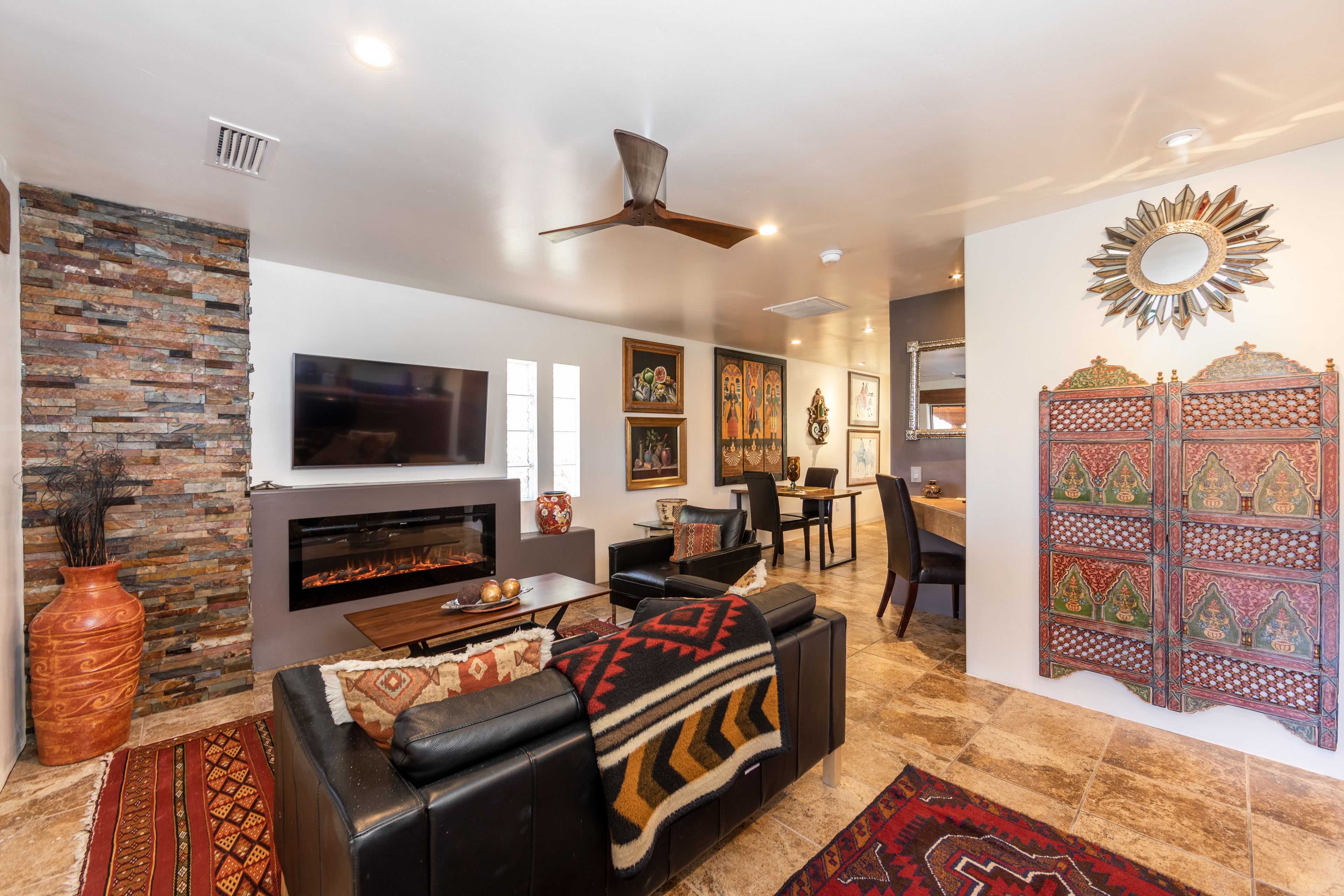 A living room with a fireplace, leather sofa, and a decorative wall panel.