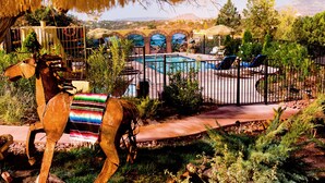Área de piscina com uma estátua decorativa de cavalo, um mural e vista para montanhas ao longe.