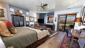 Quarto com cama, televisão, lareira e vista para as montanhas.