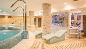 A spa area with a hot tub, lounge chairs, and a massage table.