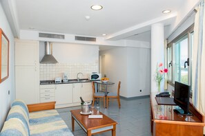 Espaço compacto com cozinha compacta, área de refeições e sala de estar com sofá e mesa de centro.