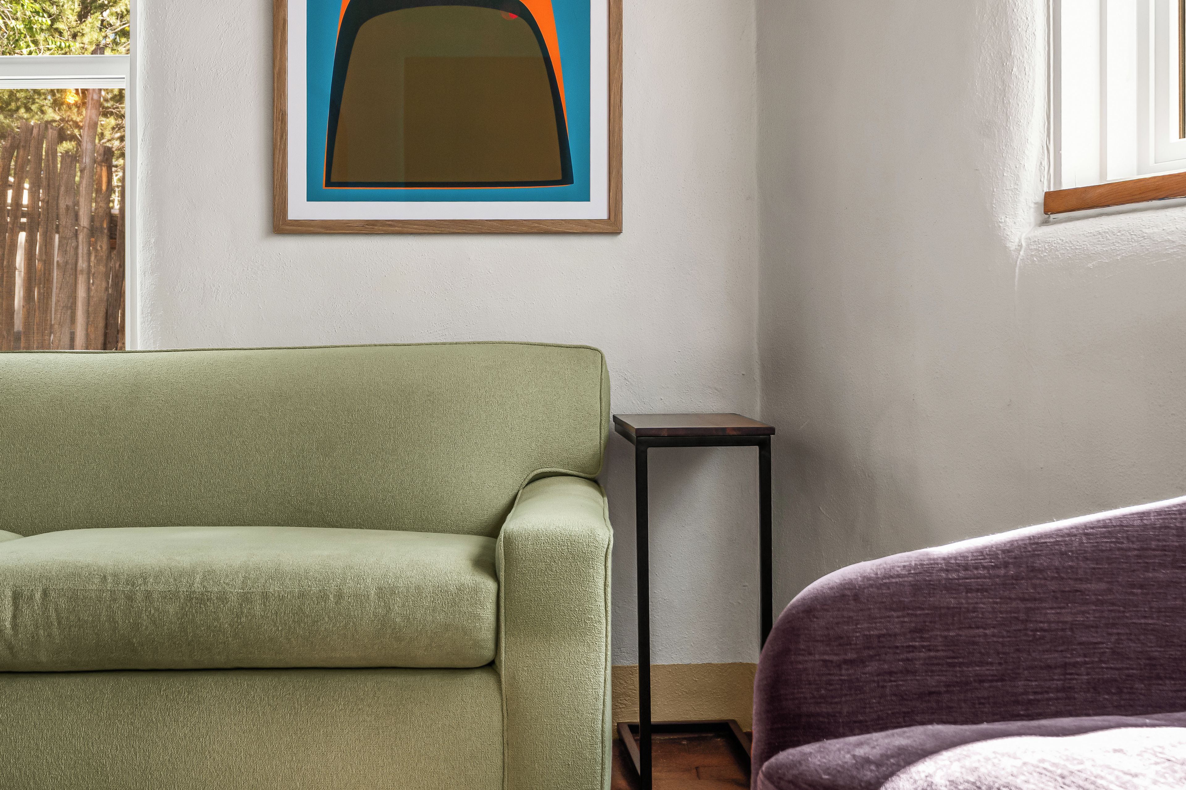 A room with a green sofa, a small black table, and a purple chair.