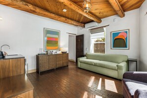 A modern living room with a wooden ceiling, a green sofa, a wooden cabinet, and artwork on the walls. - The Parador (Santa Fe)