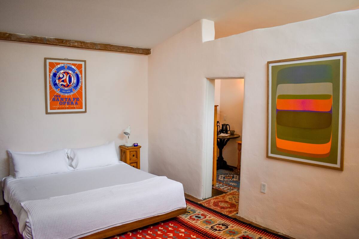 Une chambre à coucher avec un lit, une table de chevet, une affiche encadrée et un tableau au mur.