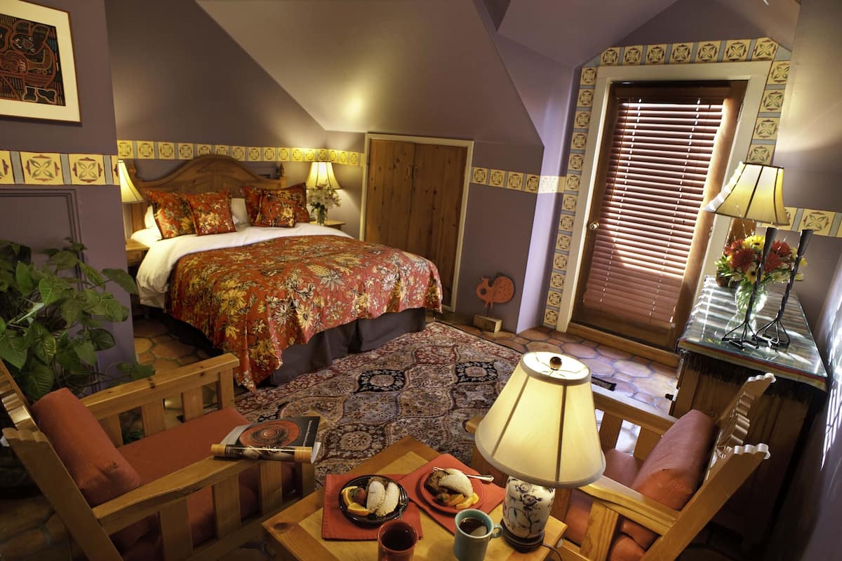 Une chambre confortable avec un grand lit, une table de chevet en bois, une table avec une lampe et une chaise.