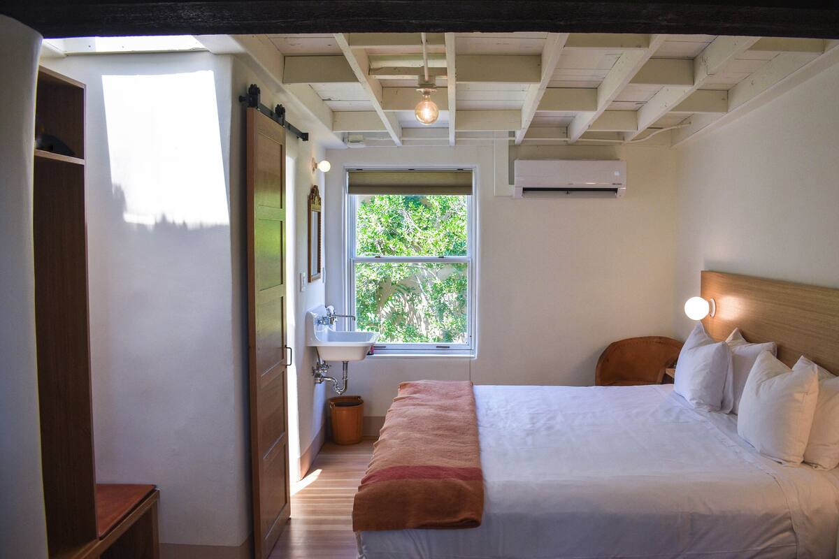 Une chambre à coucher avec un lit, une fenêtre, un lavabo et une tête de lit en bois.